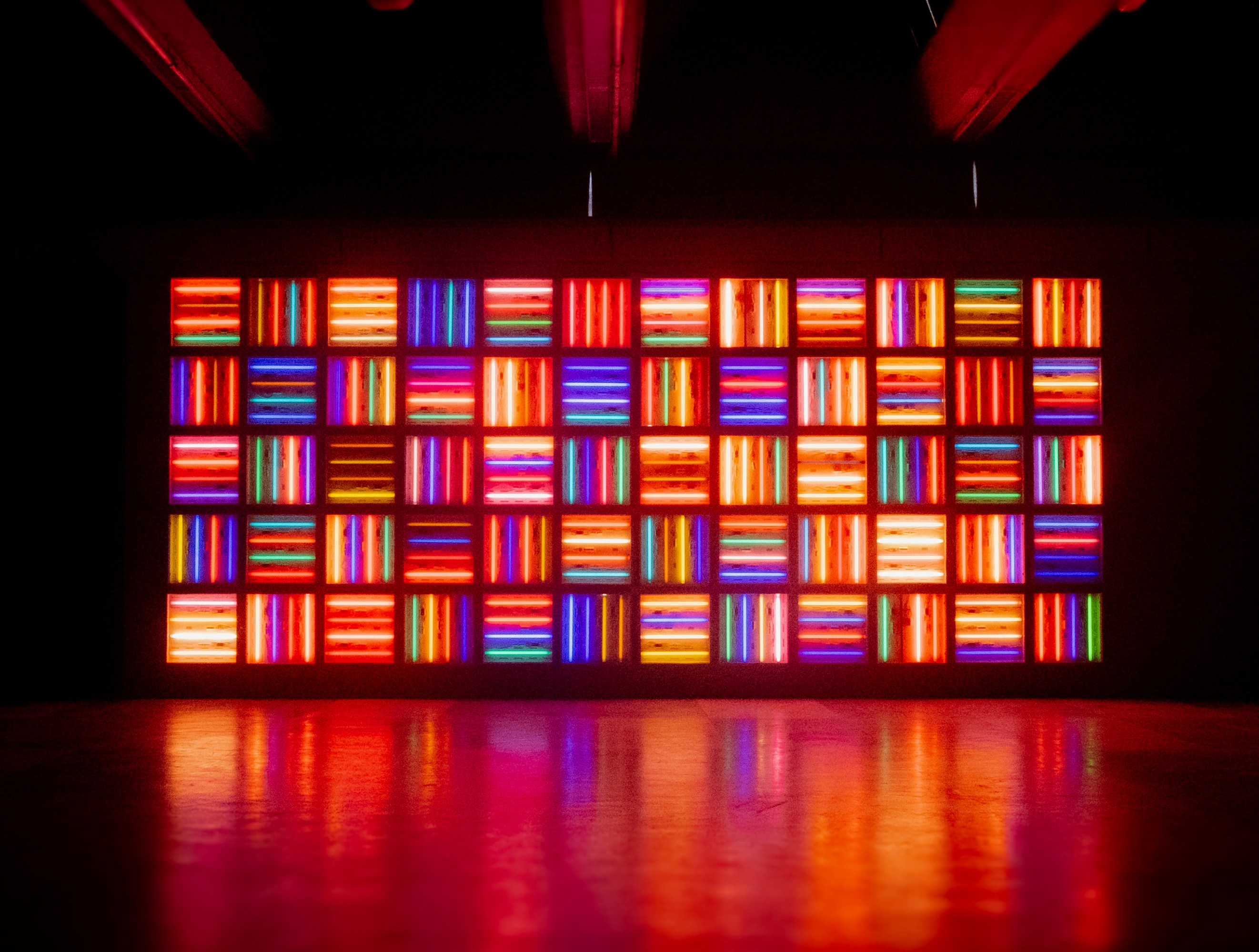 A wall of multicolored neon light rectangles in a dark room.