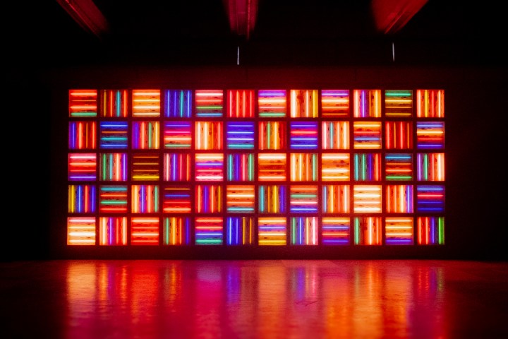 A wall of multicolored neon light rectangles in a dark room.