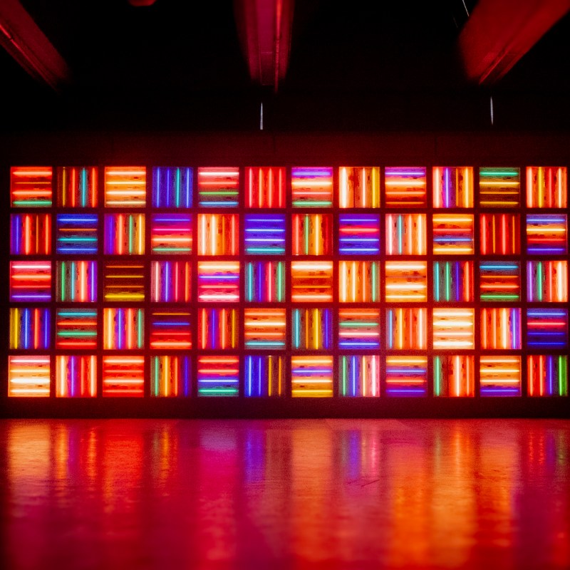 A wall of multicolored neon light rectangles in a dark room.